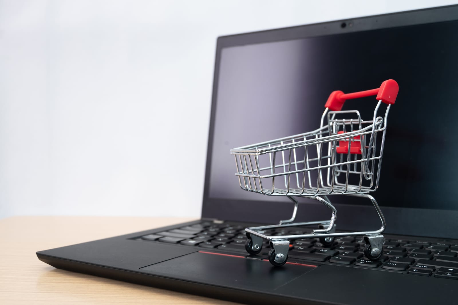 Carrito de la compra en miniatura sobre el teclado de un portátil