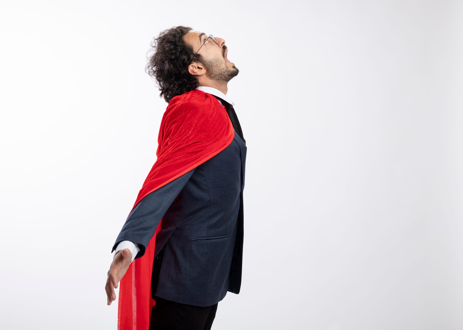 Un hombre con gafas y traje, con una capa roja de superhéroe, mira hacia arriba